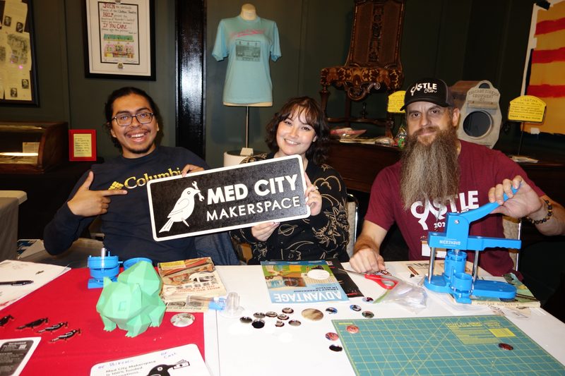 Volunteers standing behind the Med City Makerspace table at a convention